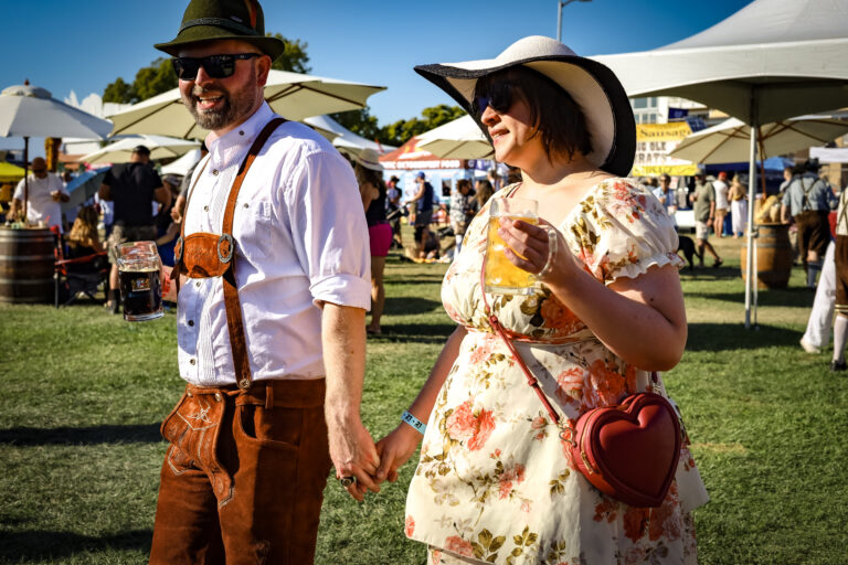 Festival attendees dressed in authentic Bavarian Lederhosen and Dirndl raising beer steins