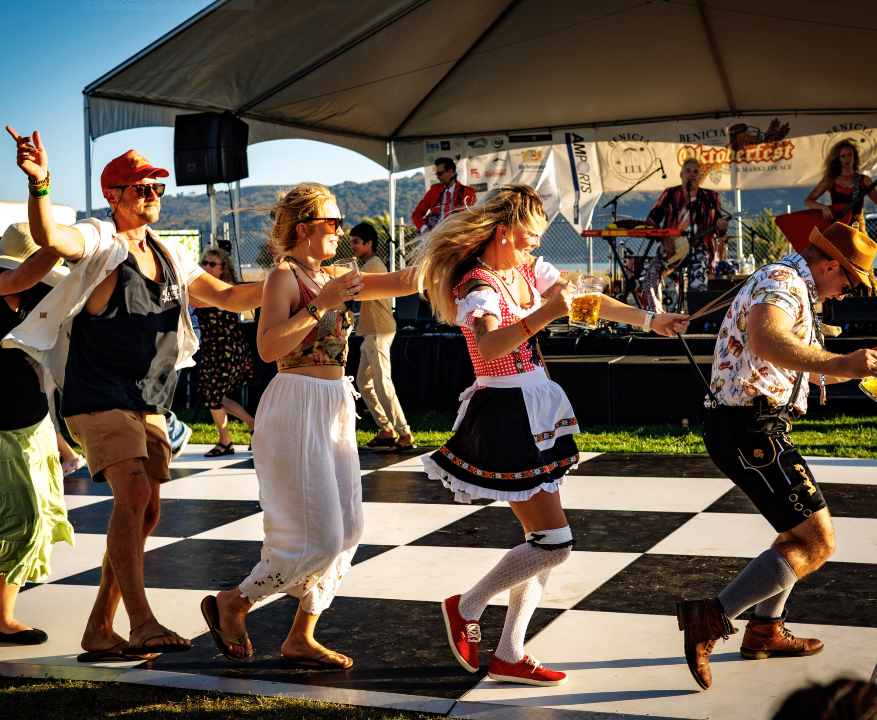 Festival attendees dancing on the checkered dance floor in front of the live music stage