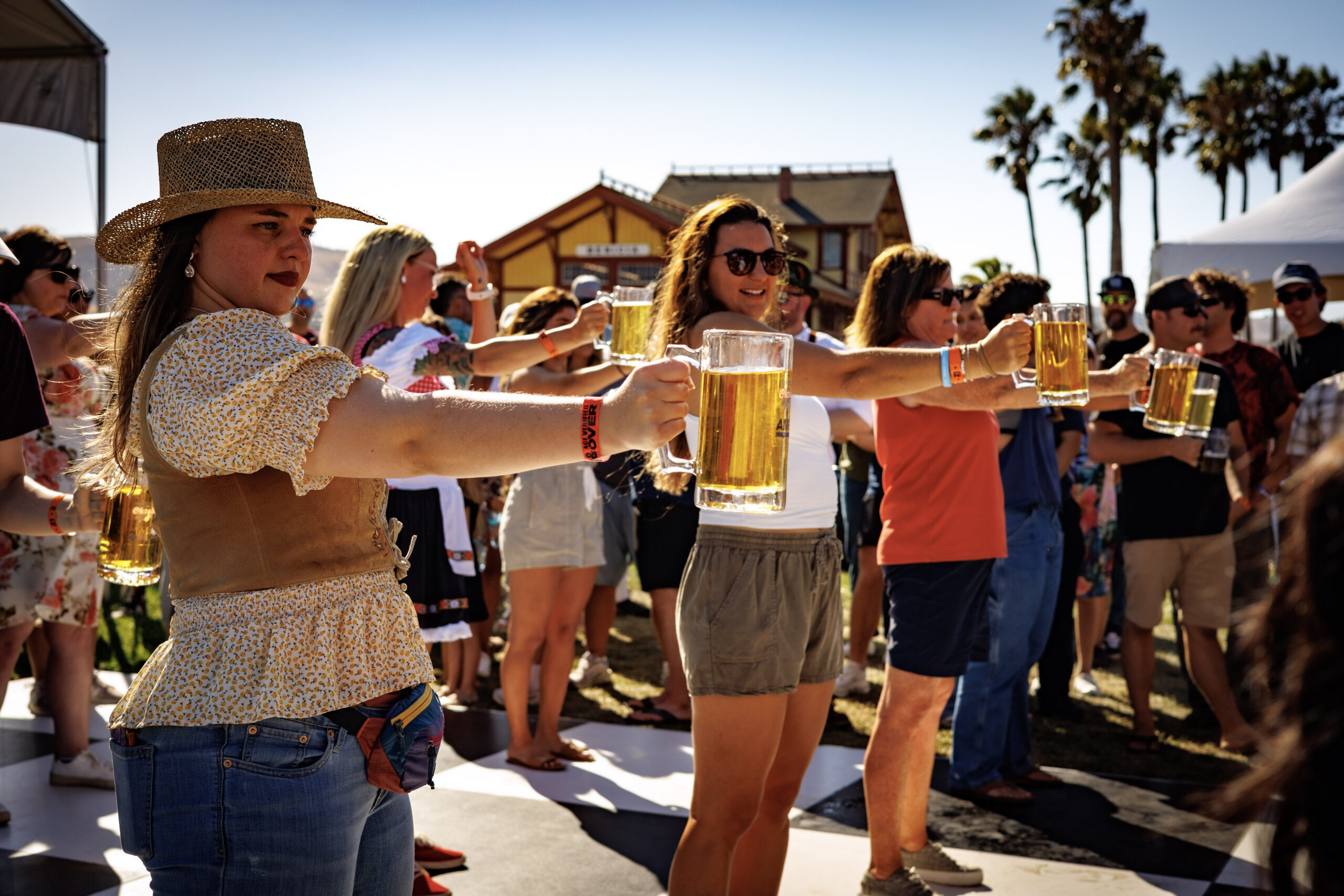Competitors holding heavy glass beer steins with arms outstretched in the official Masskrugstemmen stein-holding contest